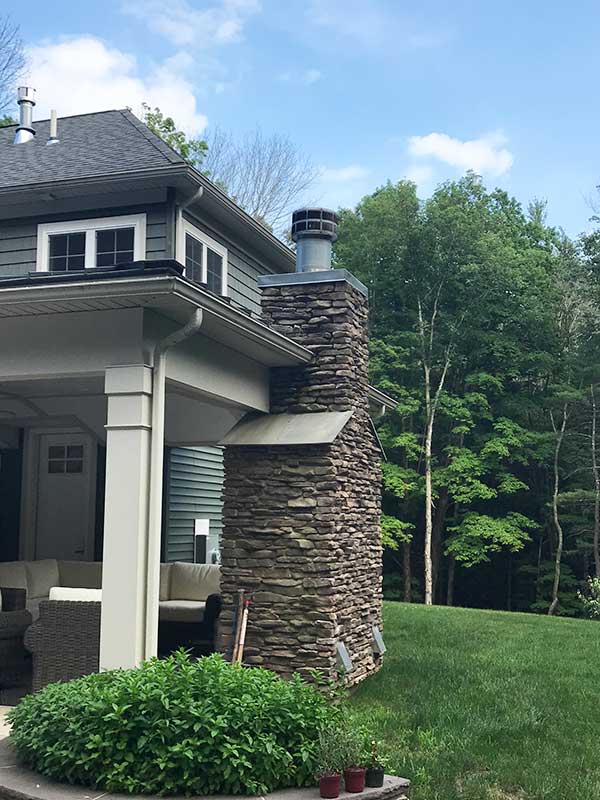 Stone Chimney with stacked stone on House with beautiful woods in background - Lackawanna County PA - Integrity Chimney Service
