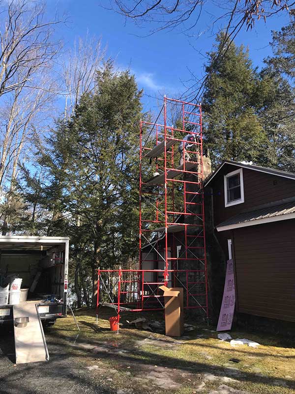 Scaffolding & Chimney Construction scaffolding with tech on top of roof and truck to the side blue sky - Lackawanna County PA - Integrity Chimney Service