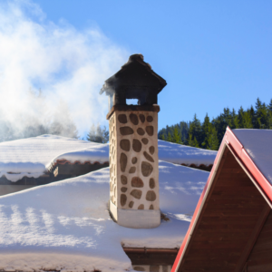 a chimney with smoke coming out surrounded by a snowy roof