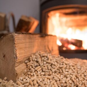 a wood log and wood pellets with a wood stove with fire burning in the background