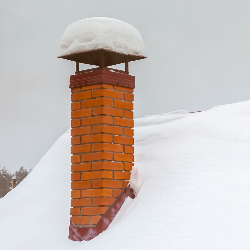an orange masonry chimney with a snow-covered cap surrounded by a very snowy roof